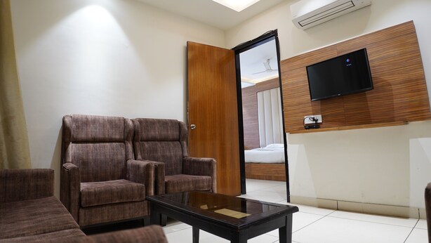 Une chambre d’hôtel moderne dotée d’un grand lit, d’un téléviseur à écran plat fixé au mur, d’un ventilateur de plafond et d’un décor mural en panneaux de bois.