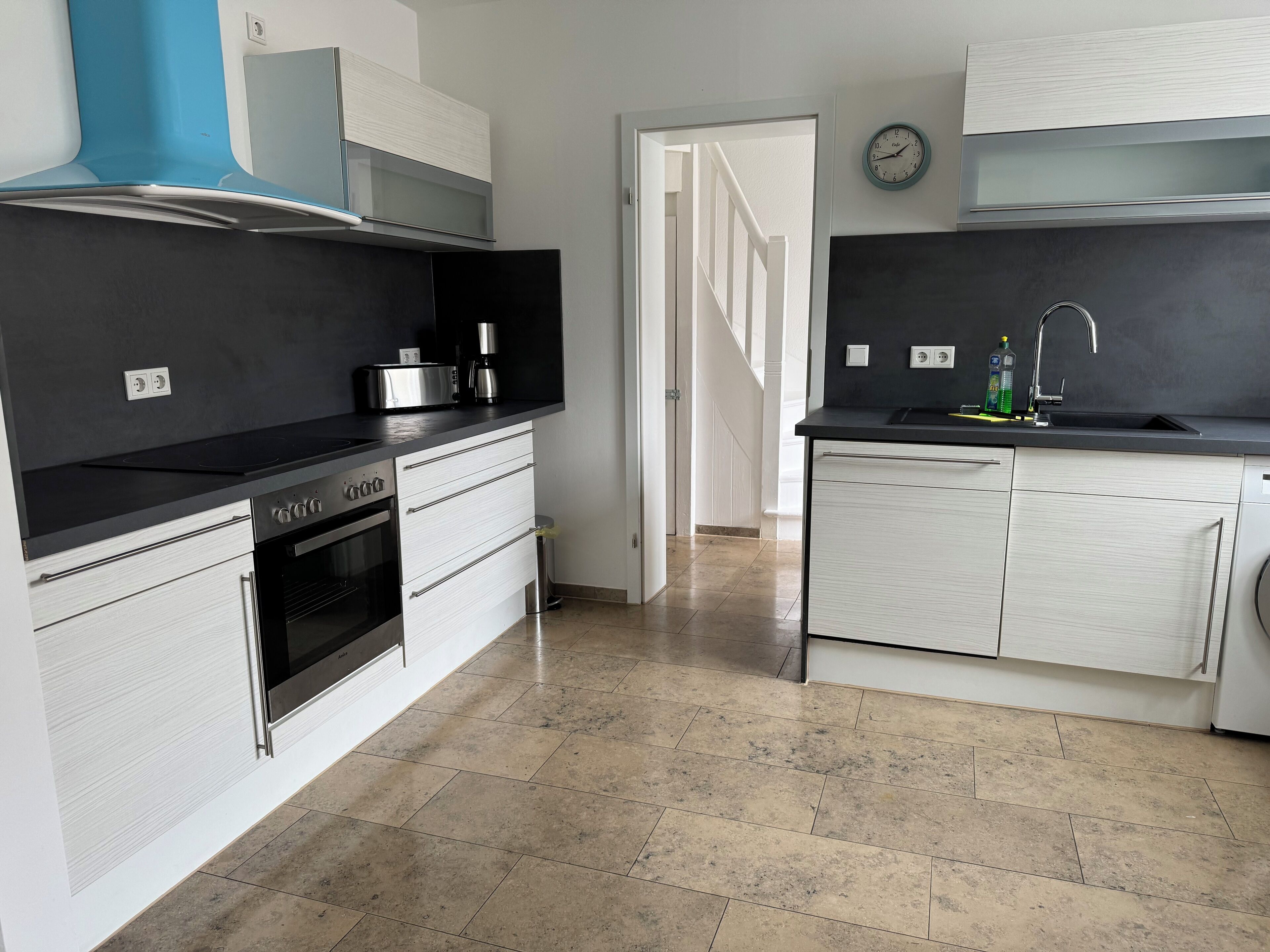 Eine moderne Küche mit Backofen, Kaffeemaschine und Spüle.