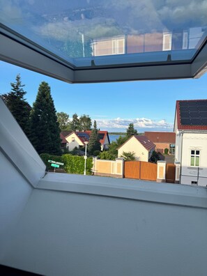 Janela de claraboia com vista para casas residenciais e um céu limpo.