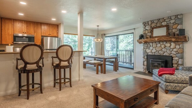 A modern kitchen with wooden cabinets, a built-in microwave, and a stone fireplace. - Summit #27: 1  BR, 1  BA Condominium in Mammoth Lakes, Sleeps 4 (Mammoth Lakes)