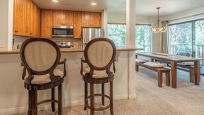 A kitchen with wooden cabinets, stainless steel appliances, and a breakfast bar with two bar stools. - Summit #27: 1  BR, 1  BA Condominium in Mammoth Lakes, Sleeps 4 (Mammoth Lakes)