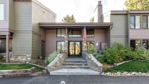 A two-story building with a stone entrance, an American flag, and a well-maintained garden. - Summit #27: 1  BR, 1  BA Condominium in Mammoth Lakes, Sleeps 4 (Mammoth Lakes)