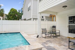 A backyard with a swimming pool, a covered patio area with chairs, and a white fence. - 6br sleeps 24 w/pool & hot tub, golfcart (North Myrtle Beach)