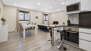 Una cocina moderna con comedor, un taburete de bar y un sofá.