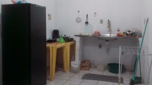 Eine kleine Küche mit Kühlschrank, Spüle und grundlegender Ausstattung.