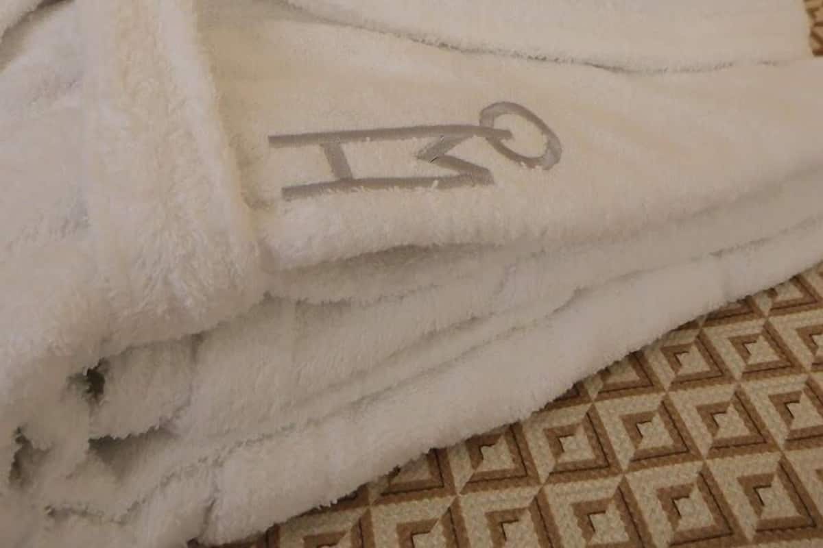 Una cama bien hecha con sábanas blancas y una toalla doblada al lado.