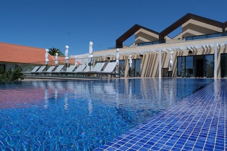 Una piscina al aire libre, sillones reclinables de piscina