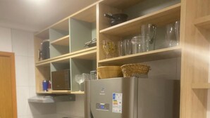 Une cuisine dotée d’un réfrigérateur en acier inoxydable, d’étagères en bois et d’un plan de travail noir.