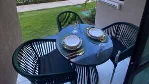 Un balcon avec une table dressée pour deux personnes, donnant sur une piscine et un immeuble doté de nombreux balcons.