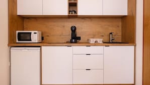 A compact kitchen with a microwave, coffee maker, and a small refrigerator.