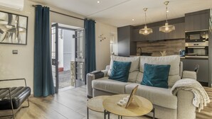 Ein modernes Wohnzimmer mit einer Couch, einem Couchtisch und einer Küchenzeile im Hintergrund.