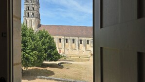 Uitzicht door een raam op een gebouw met een hoge toren en een binnenplaats.