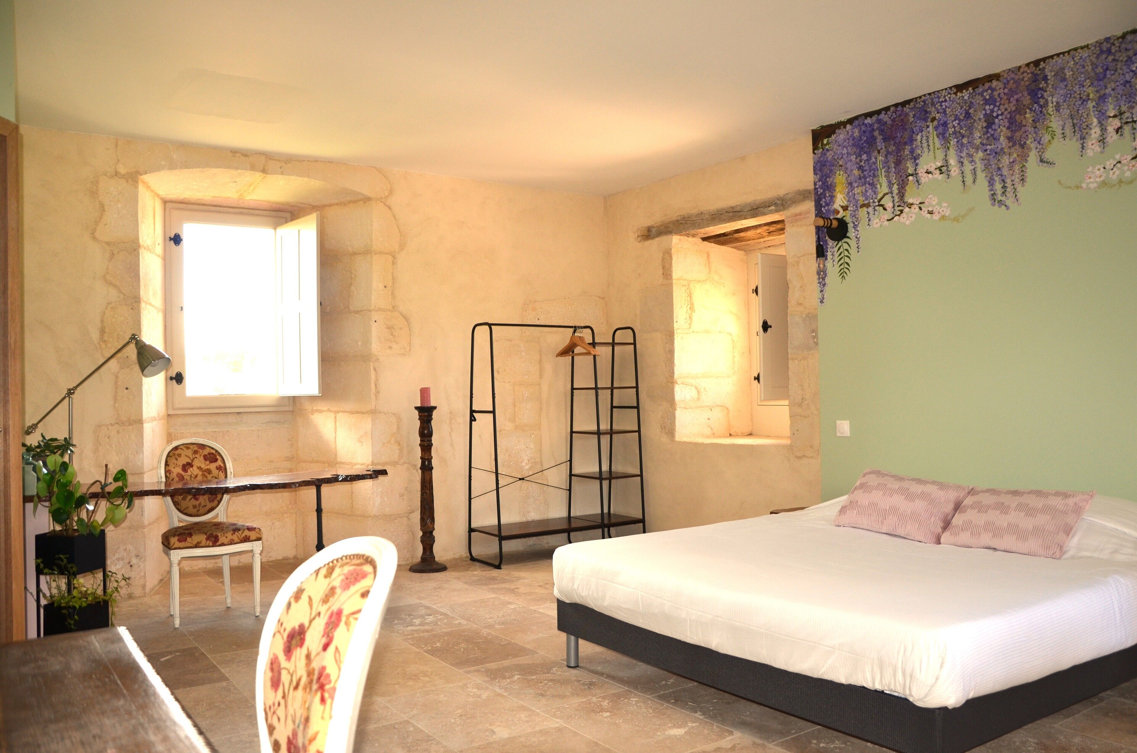 A bedroom with a bed, a chair, a desk, and a window.