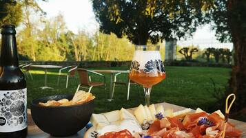 Um piquenique montado com uma garrafa, tigela, prato de queijo e copo de vinho ao ar livre.