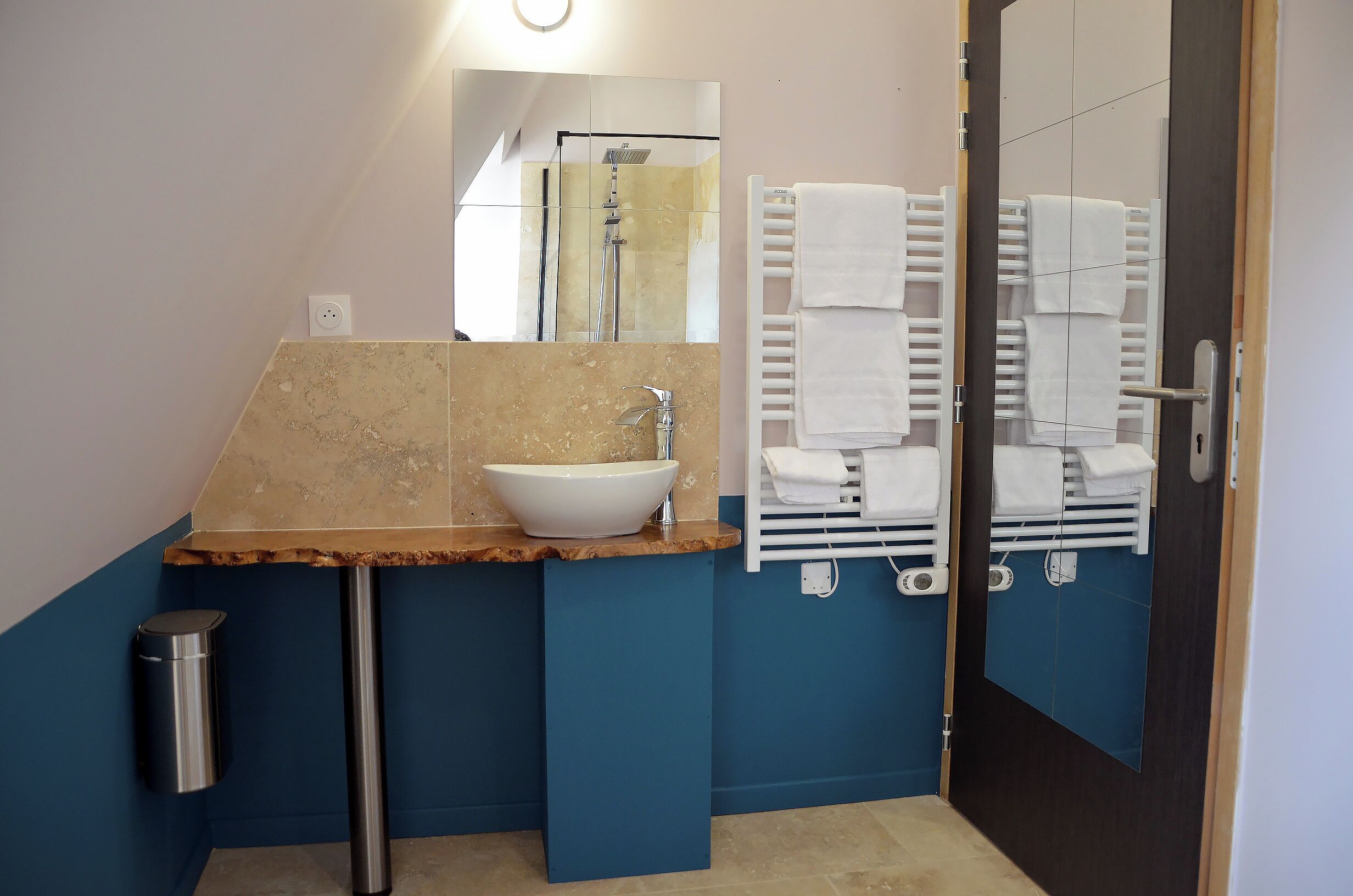 A bathroom with a marble sink, a mirror, a towel rack, and a door.