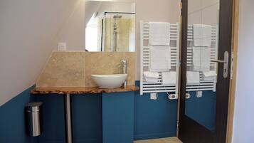 A bathroom with a marble sink, a mirror, a towel rack, and a door.