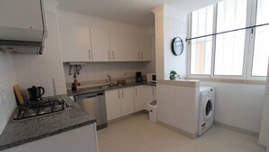 Una cocina moderna con armarios blancos, estufa a gas, lavavajillas y lavadora.