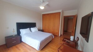 A bedroom with a bed, wooden wardrobe, nightstand, and a ceiling fan. - Aqua Vista Lido Apartment by IZI Holiday Rentals, Aqua Vista Lido Apartment (Funchal)