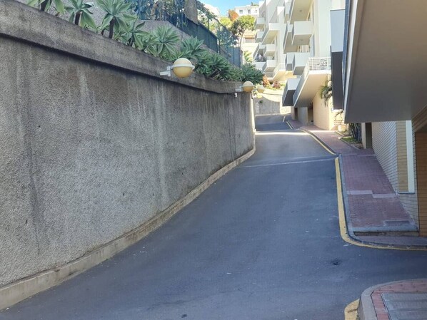 Une rue étroite, bordée d’un côté par un mur en béton et de l’autre par un immeuble.