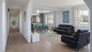 A spacious living area with a sofa, a coffee table, and a dining area with chairs. - Paul's Holiday House, Paul's Holiday House (Ponta Do Pargo)