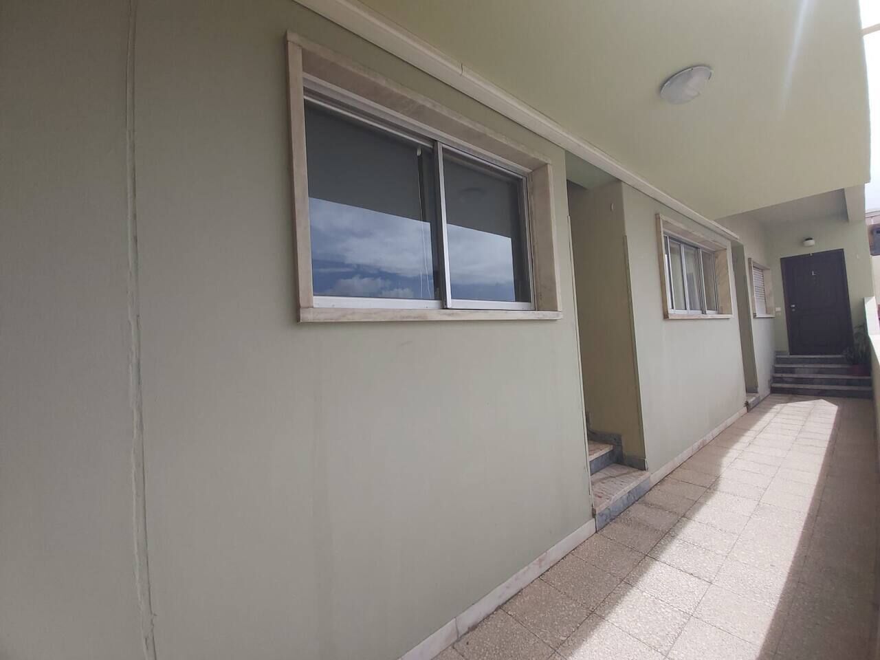 A building with a light-colored exterior, a tiled floor, and a window with a view of the sky.
