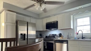 A modern kitchen with white cabinets, stainless steel appliances, a dishwasher, and a window providing natural light. - Corner Cottage 2 bedroom pets welcome and close to downtown (Ashland)