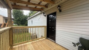 A wooden deck with a black door and a green chair. - Corner Cottage 2 bedroom pets welcome and close to downtown (Ashland)