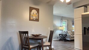A dining area with a round table and two chairs, a ceiling fan, and a painting on the wall. - Corner Cottage 2 bedroom pets welcome and close to downtown (Ashland)