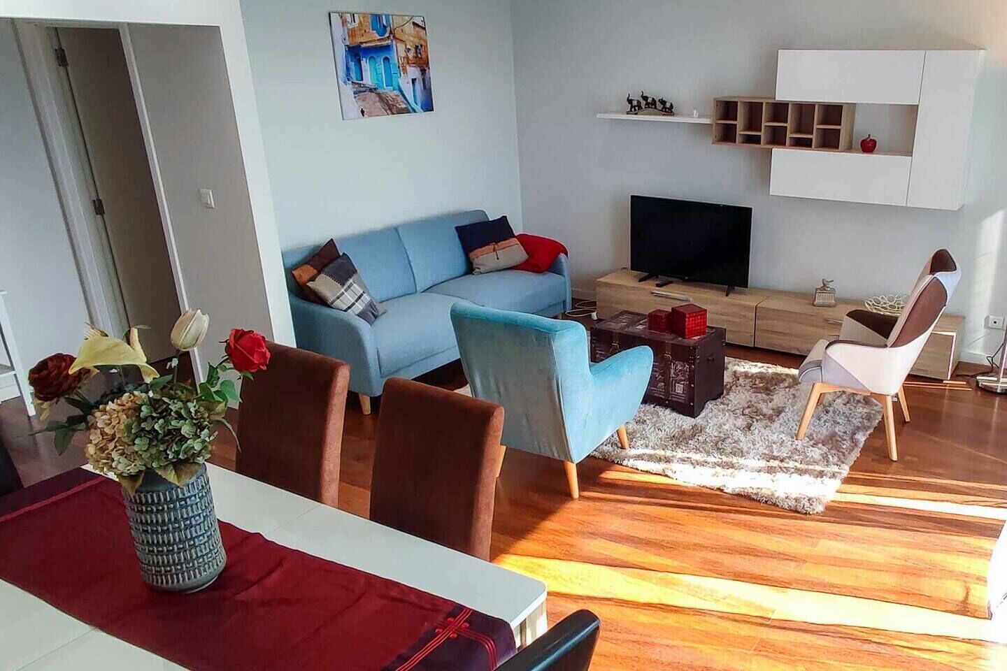 Uma sala de estar moderna com um sofá azul, uma TV e uma mesa de centro de madeira.