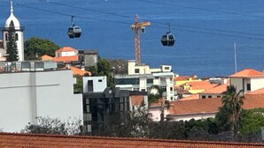 A coastal town with a cable car system, buildings with red-tiled roofs, and a church spire.