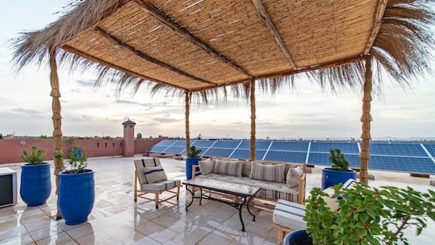 A rooftop terrace with a thatched roof, seating area, and potted plants. - Luxury stay near Marrakech with mountain views, pool, and family fun (Marrakesh)