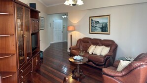 A spacious living room with a brown leather sofa, a wooden cabinet, and a round coffee table. - Robert Apartment in Ajuda (Funchal)