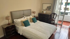A bedroom with a bed, nightstands, a dresser, a chair, and a mirror. - Robert Apartment in Ajuda (Funchal)