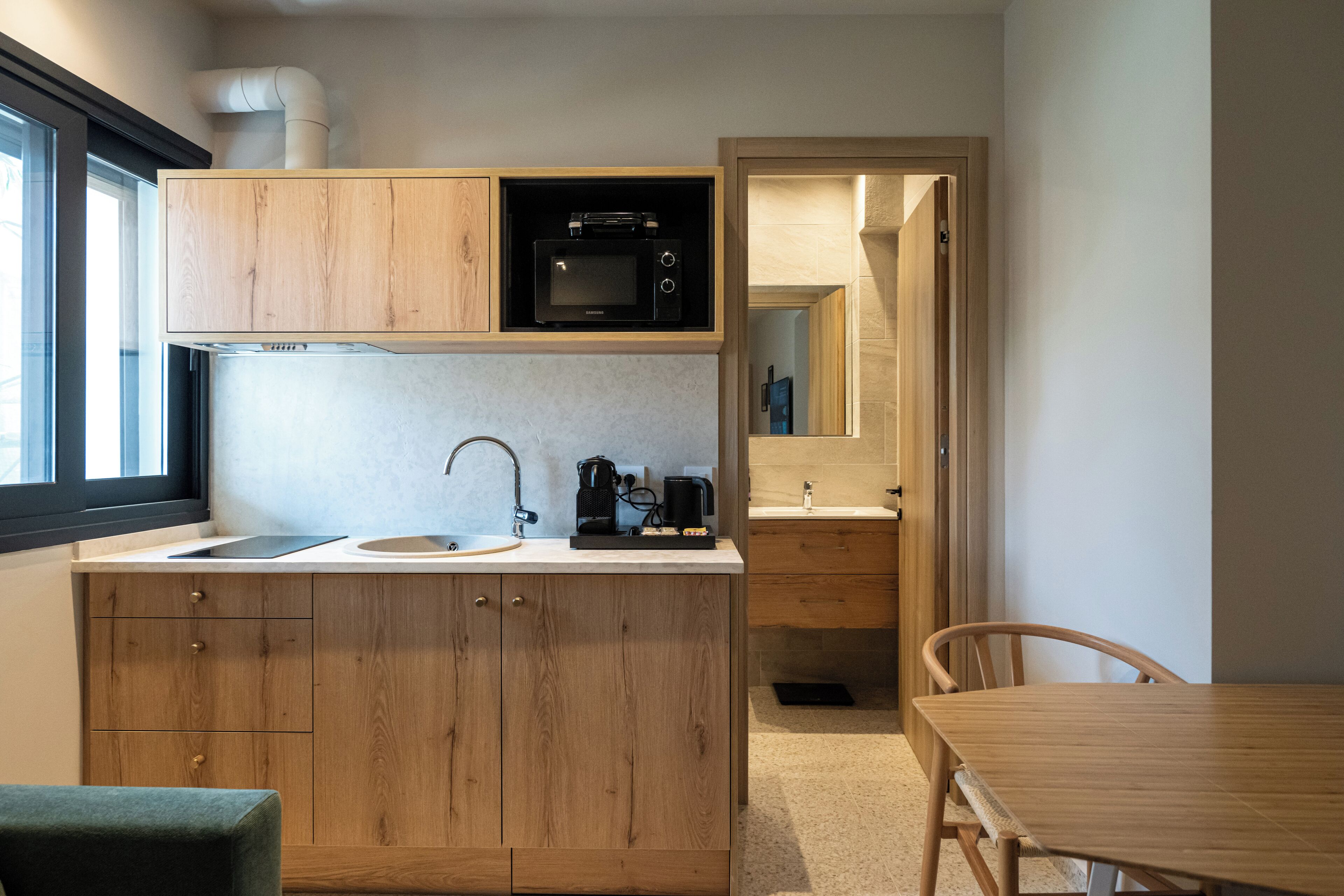 A compact kitchen with wooden cabinets, a microwave, a coffee maker, and a sink.