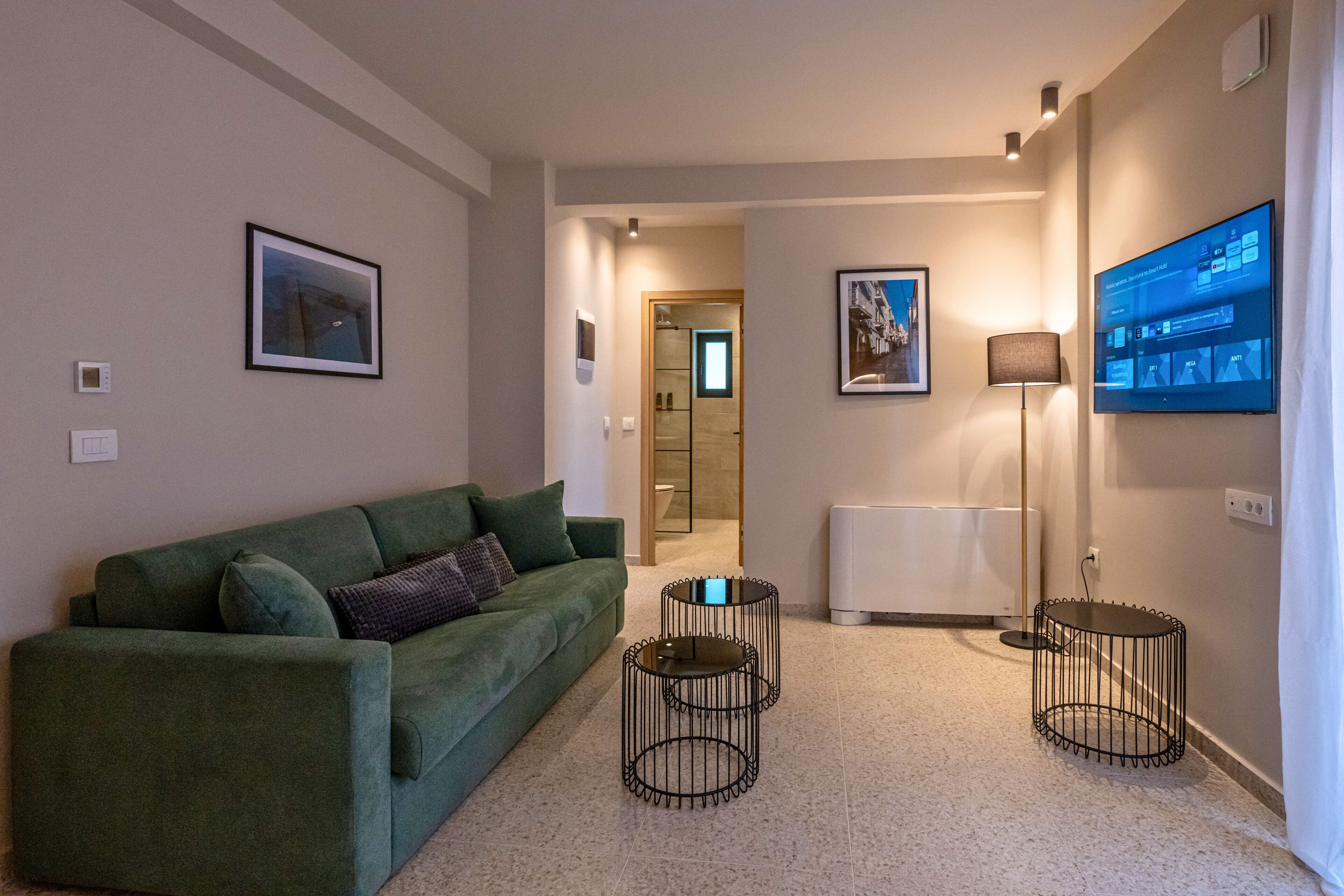 A modern living room with a green sofa, a flat-screen TV, and a small coffee table.