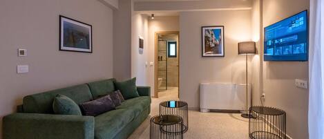 A modern living room with a green sofa, a flat-screen TV, and a small coffee table.