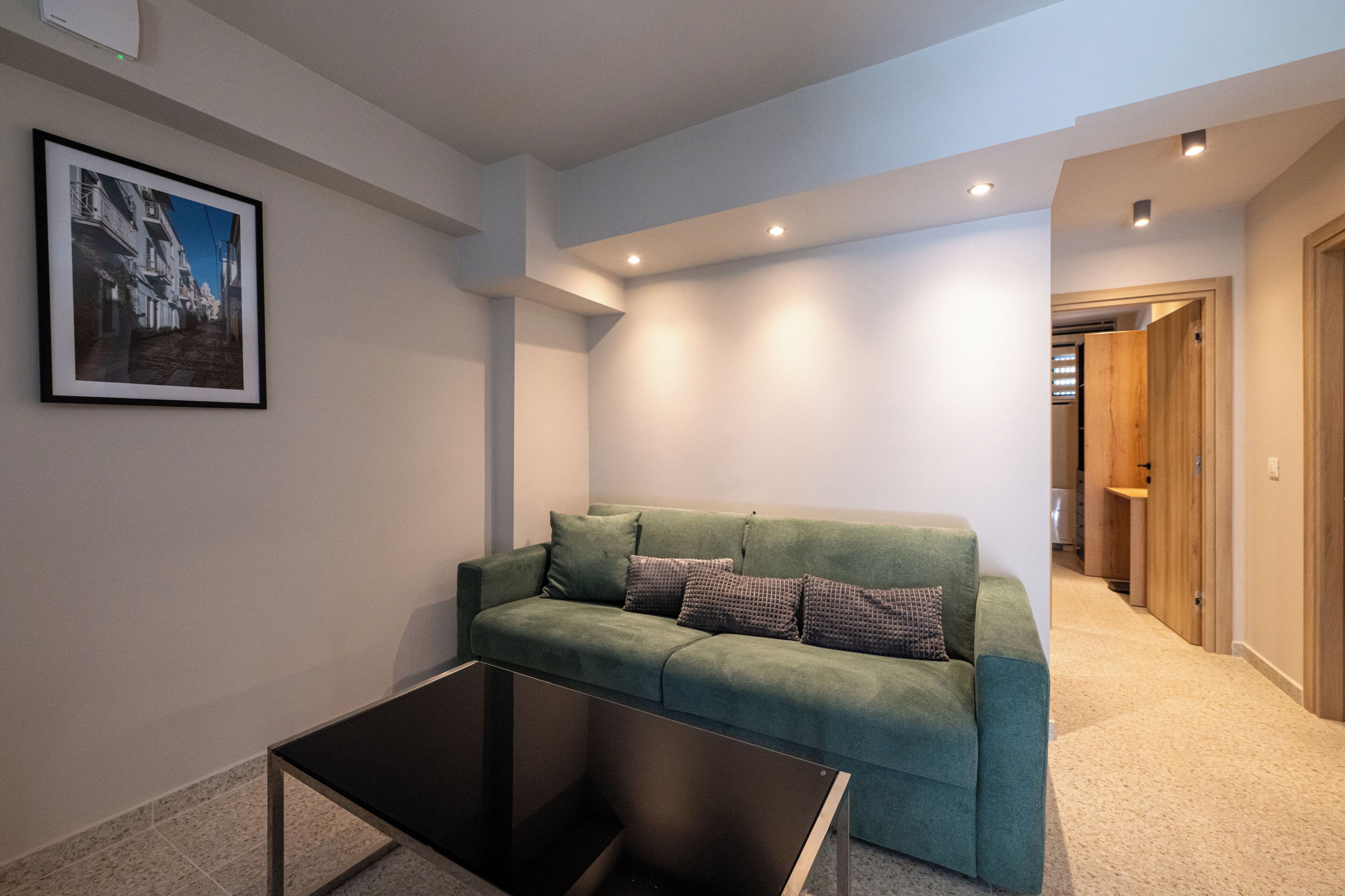 A modern living room with a green sofa, a coffee table, and a framed picture on the wall.