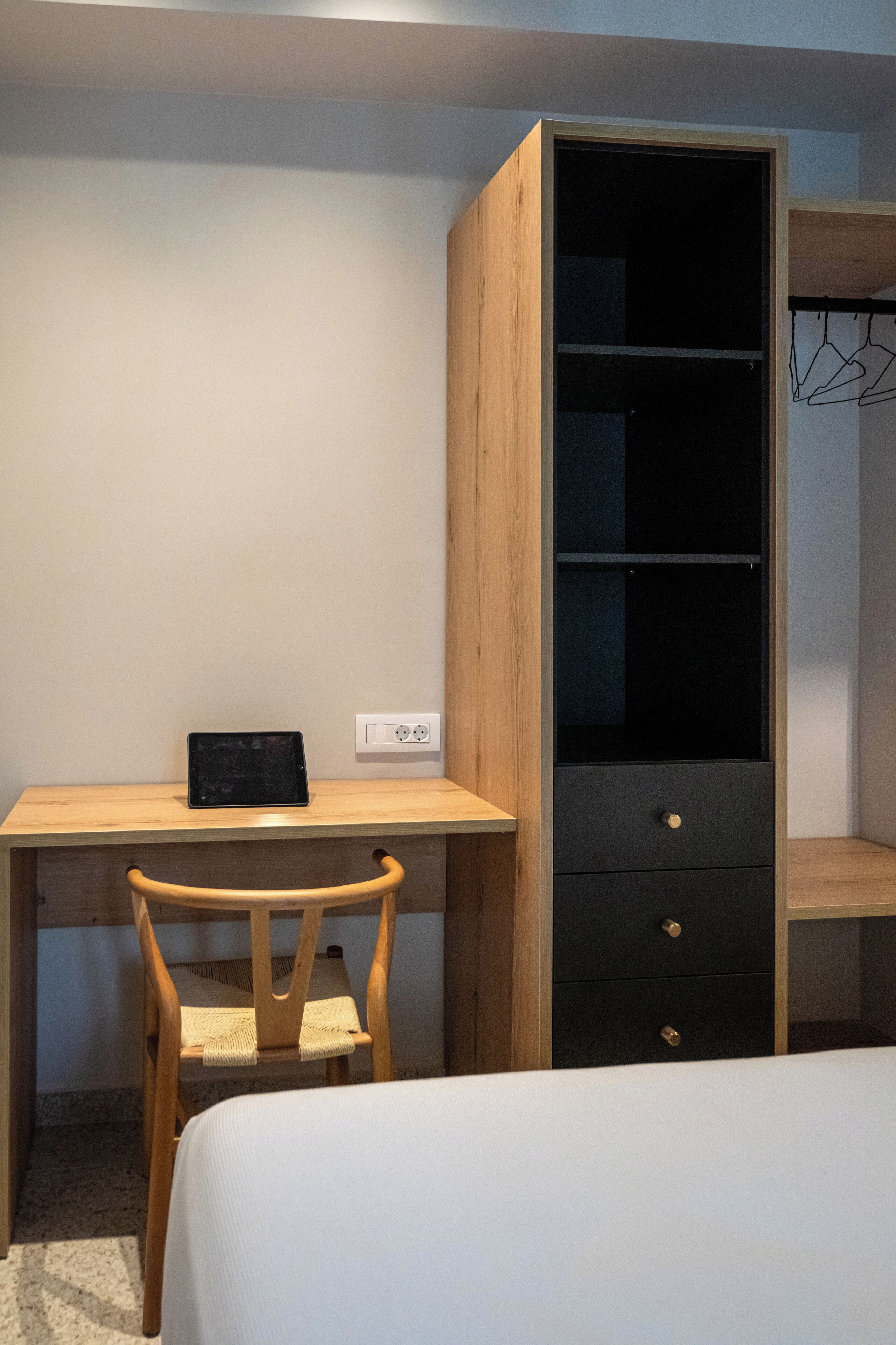 Un dormitorio con un escritorio de madera, una silla, una cama y un armario.