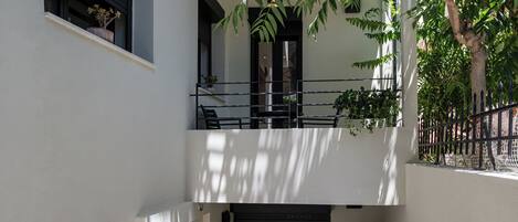 A two-story building with a balcony on the upper floor, potted plants, and a metal fence.