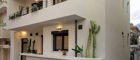 Ein modernes, zweistöckiges Gebäude mit Balkonen und einer flachen Dachterrasse, mit der Aufschrift "ASKLIPIOU CUBE".