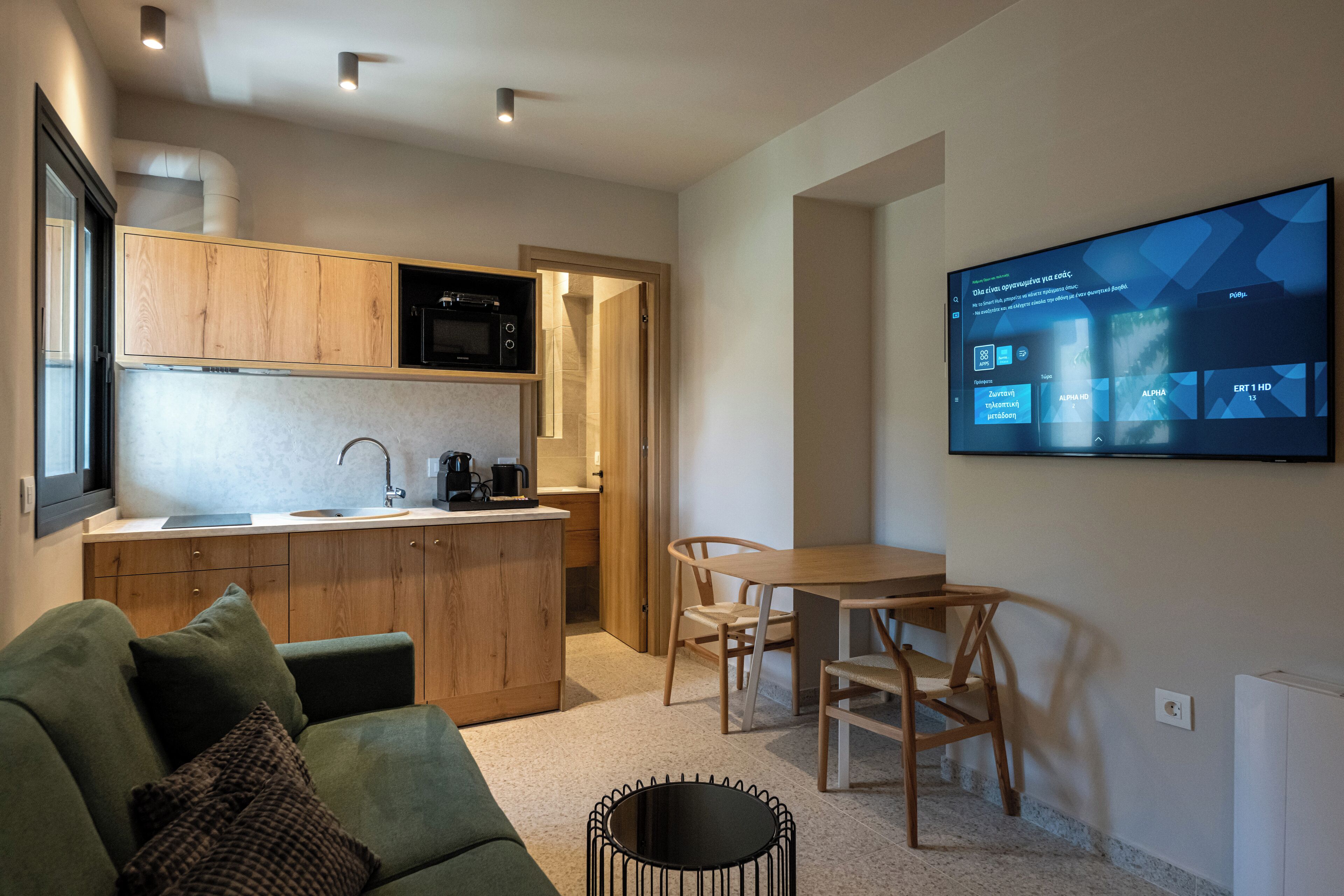 Un espacio habitable compacto con kitchenette, zona de comedor y televisor de pantalla plana montado en la pared.