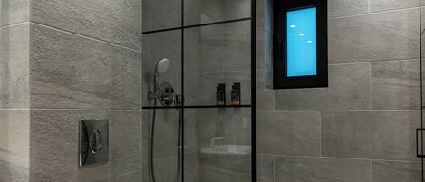A modern bathroom with a glass-enclosed shower, a white toilet, and a small window with a blue light.