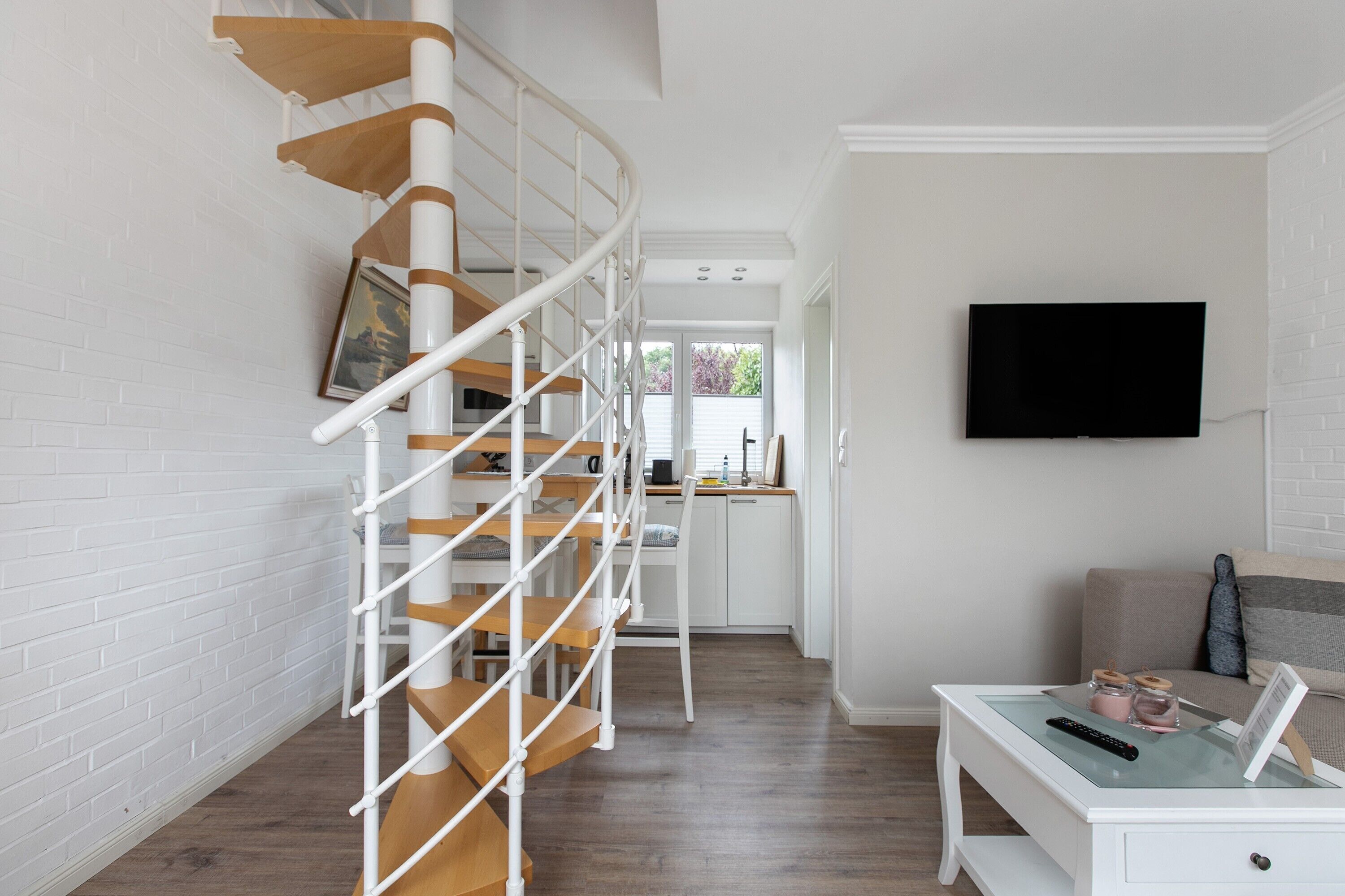 A modern interior with a spiral staircase, a flat-screen TV, and a dining area.