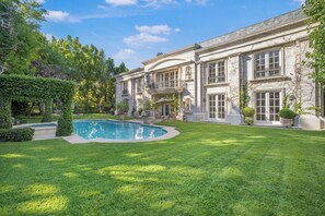 Un grand bâtiment de style classique, doté d’une piscine et d’une pelouse parfaitement entretenue.