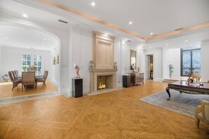 A spacious living room with a fireplace, wooden flooring, and a dining area with chairs.