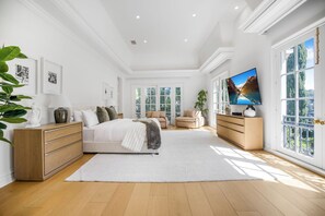 Une chambre spacieuse avec un grand lit, une télévision et une vue sur un paysage montagneux grâce à de grandes fenêtres.