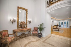 An opulent room with a grand mirror, ornate furniture, and a piano.
