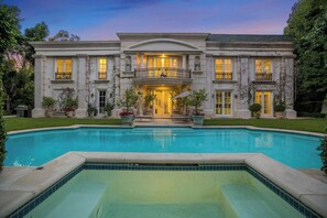 A large, stately mansion with a swimming pool in the foreground.