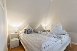 Une chambre à coucher avec un lit, des oreillers, une table de chevet et une lampe.