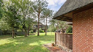 A brick building with a thatched roof, surrounded by a well-maintained lawn and trees.